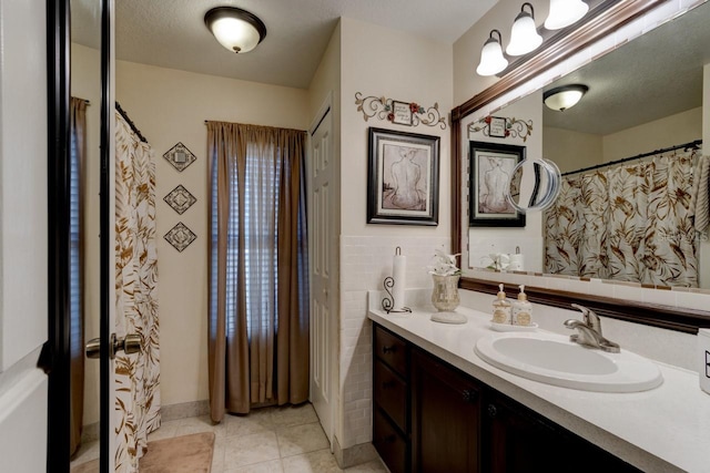 bathroom with vanity, tile patterned flooring, tile walls, and a textured ceiling