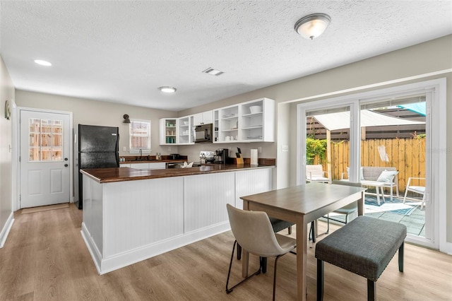 kitchen featuring white cabinetry, a textured ceiling, light hardwood / wood-style flooring, kitchen peninsula, and black appliances