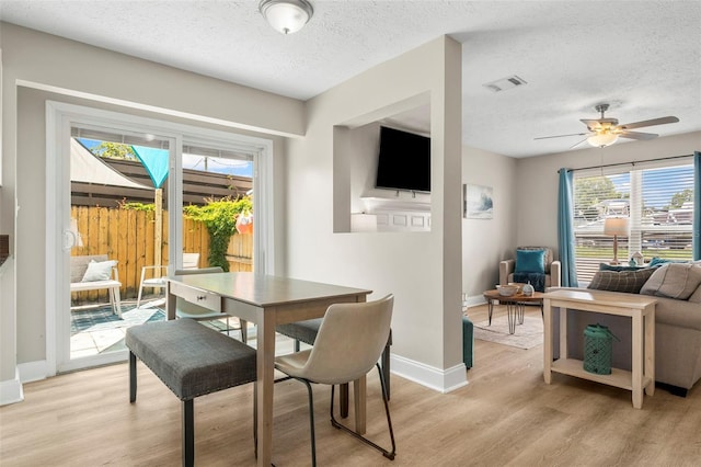 dining space with ceiling fan, light hardwood / wood-style floors, and a textured ceiling