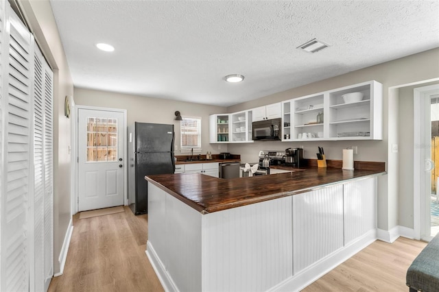 kitchen featuring black appliances, kitchen peninsula, light hardwood / wood-style flooring, and white cabinets