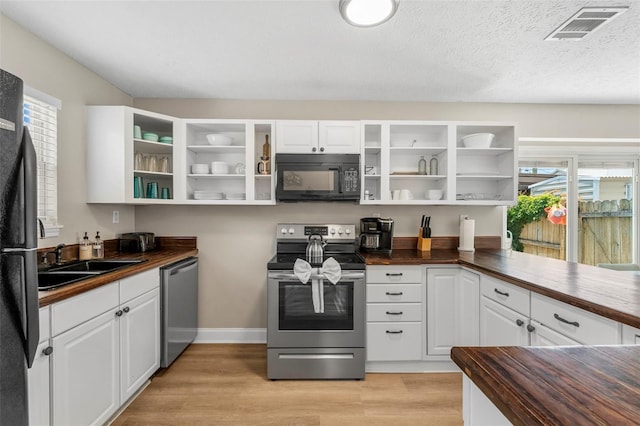 kitchen with wooden counters, sink, white cabinets, and black appliances