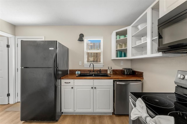 kitchen featuring wood counters, sink, white cabinetry, light hardwood / wood-style floors, and black appliances