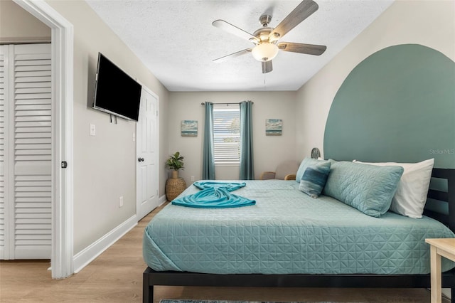 bedroom featuring ceiling fan, hardwood / wood-style floors, and a textured ceiling