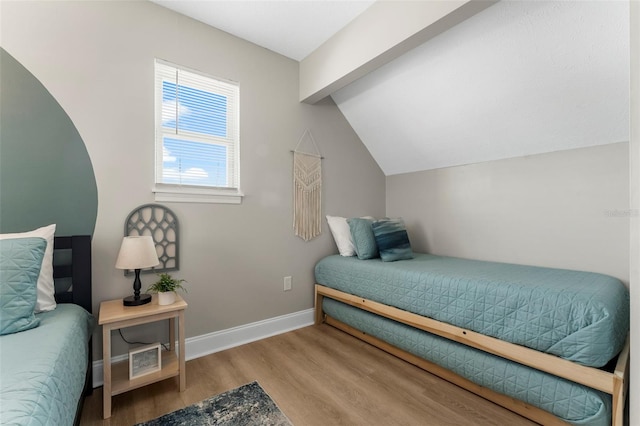 bedroom featuring lofted ceiling with beams and light hardwood / wood-style floors