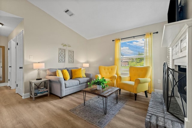 living room featuring a fireplace, vaulted ceiling, and light hardwood / wood-style flooring