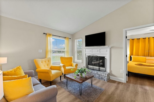 living room featuring lofted ceiling, a brick fireplace, and wood-type flooring