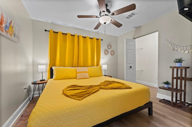 bedroom featuring hardwood / wood-style floors, a textured ceiling, and ceiling fan