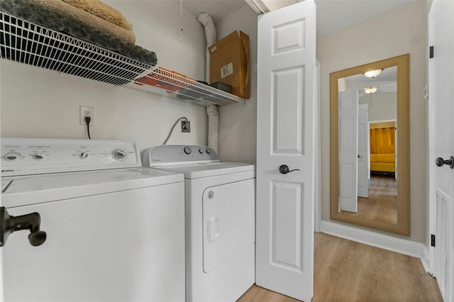 laundry area with washing machine and clothes dryer and light hardwood / wood-style flooring