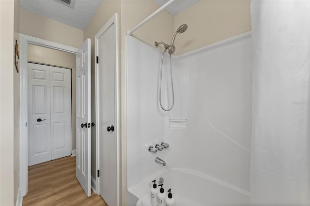 bathroom with shower / bathing tub combination, hardwood / wood-style floors, and a textured ceiling