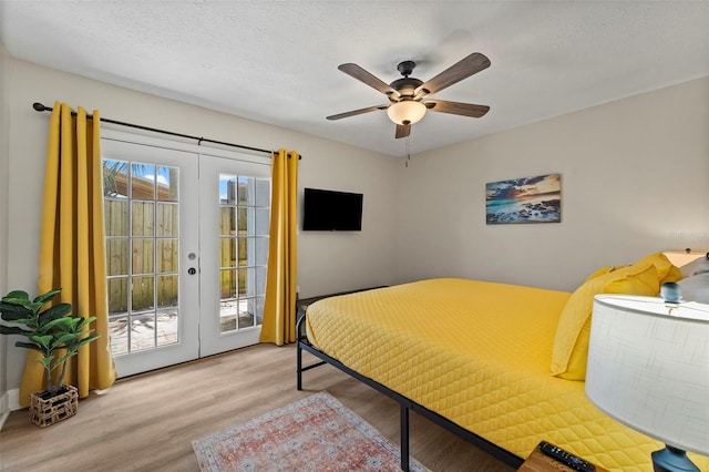 bedroom featuring french doors, access to exterior, ceiling fan, a textured ceiling, and light hardwood / wood-style flooring