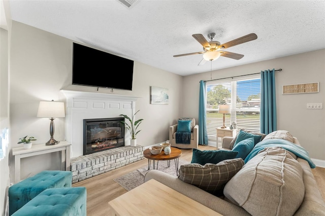 living room featuring ceiling fan, a textured ceiling, and light hardwood / wood-style flooring