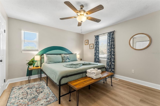 bedroom with ceiling fan, light hardwood / wood-style floors, and a textured ceiling