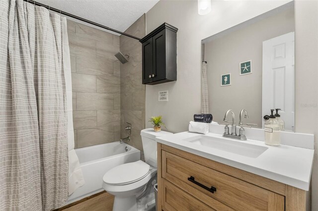 full bathroom featuring shower / bathtub combination with curtain, vanity, a textured ceiling, and toilet