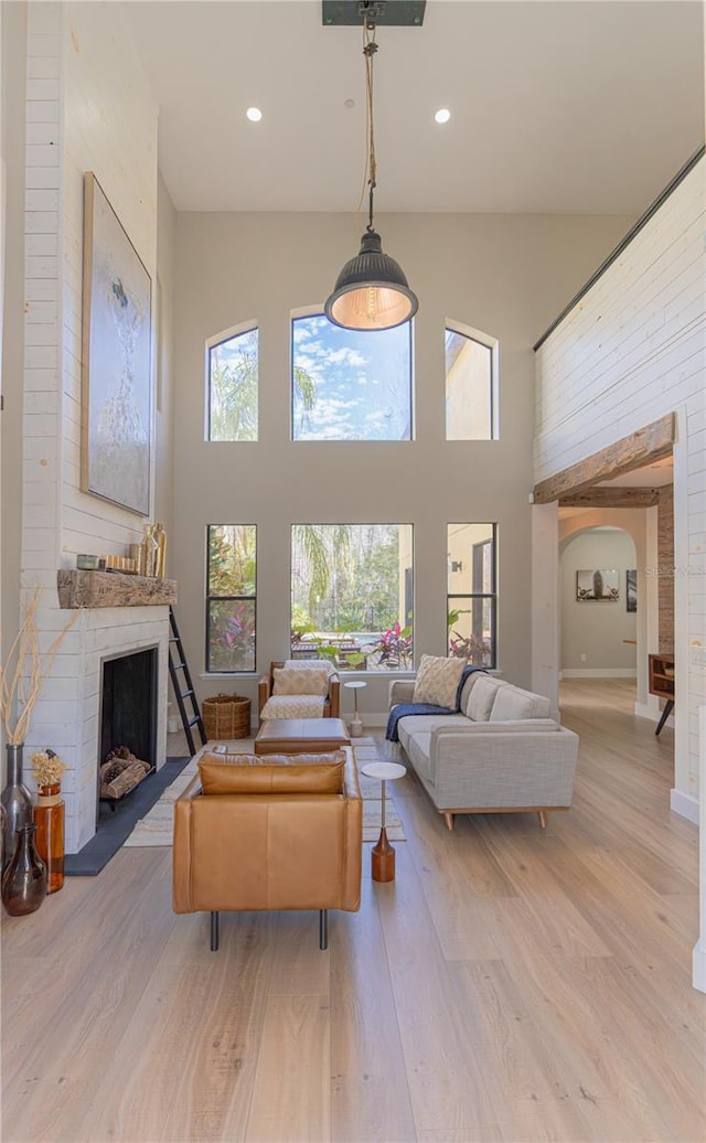 living room featuring a fireplace, light hardwood / wood-style floors, and a high ceiling