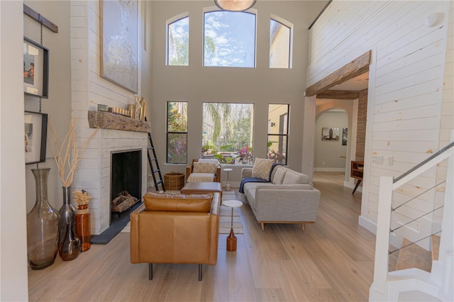 living room with a towering ceiling, a healthy amount of sunlight, and light wood-type flooring