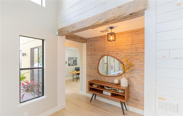 corridor with beam ceiling, light hardwood / wood-style flooring, and wood walls