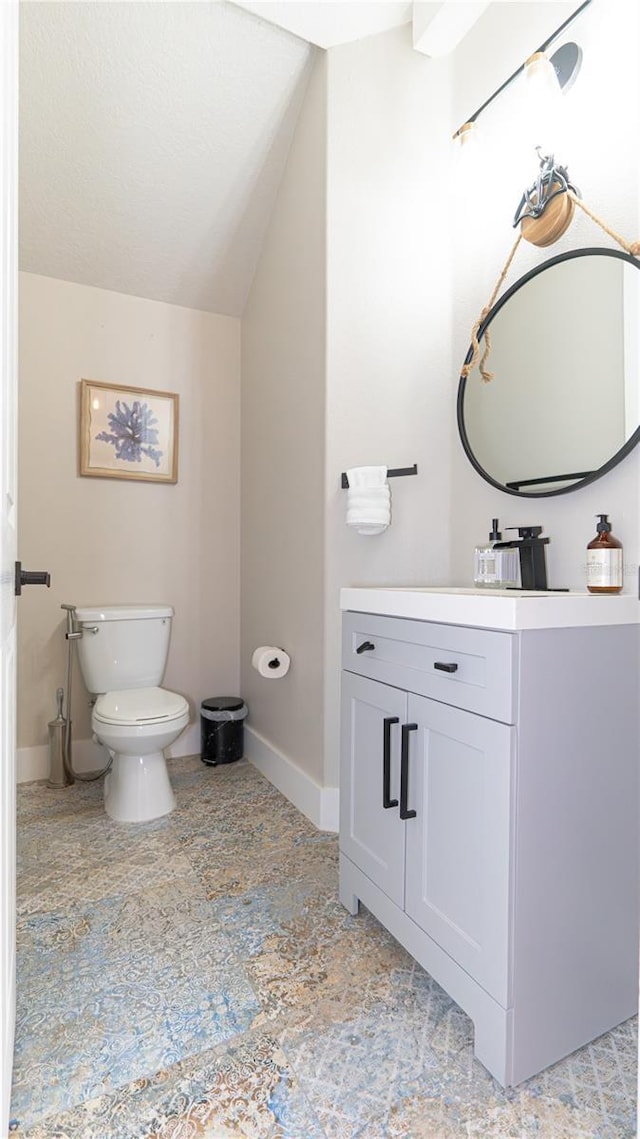 bathroom with lofted ceiling, vanity, and toilet