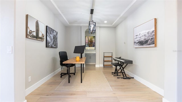 home office featuring a tray ceiling and light hardwood / wood-style floors