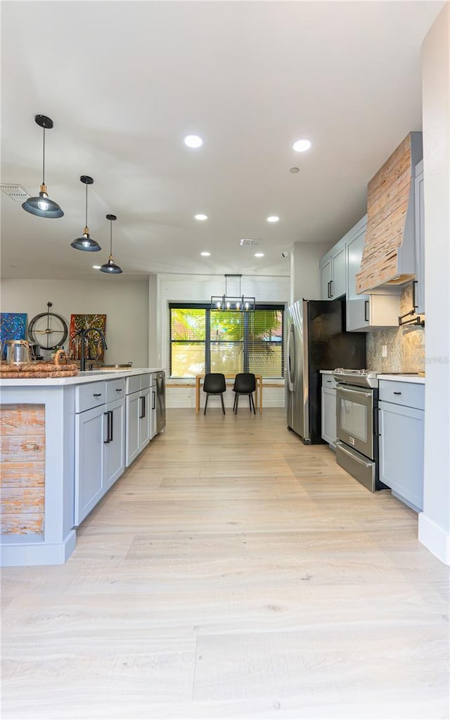 kitchen featuring pendant lighting, sink, appliances with stainless steel finishes, backsplash, and wall chimney exhaust hood