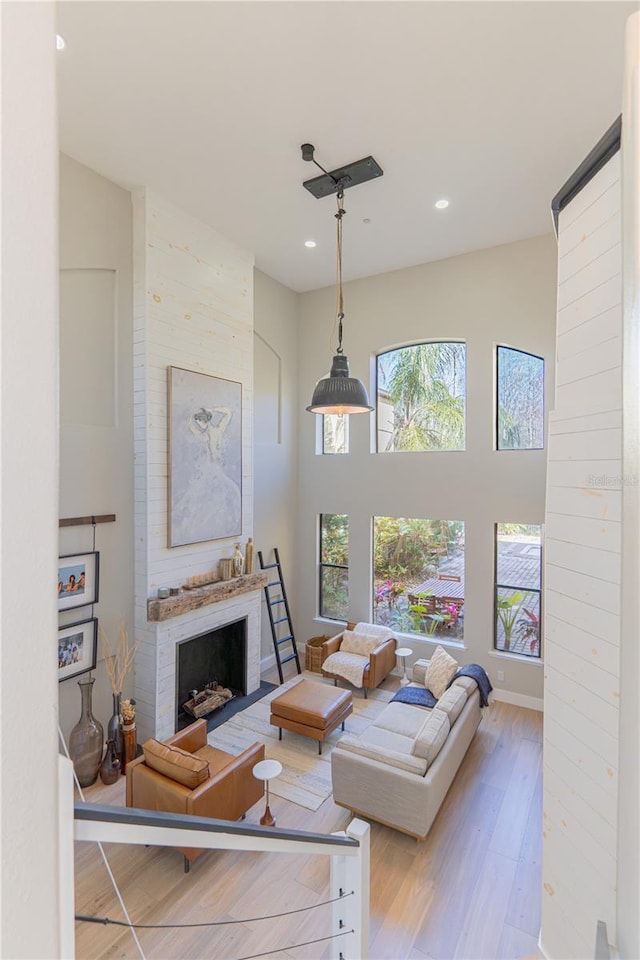 living room featuring a brick fireplace, a high ceiling, and light wood-type flooring