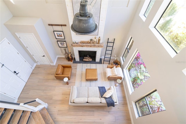 living room with hardwood / wood-style flooring, a towering ceiling, and a fireplace