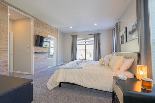 carpeted bedroom with ensuite bathroom and wood walls