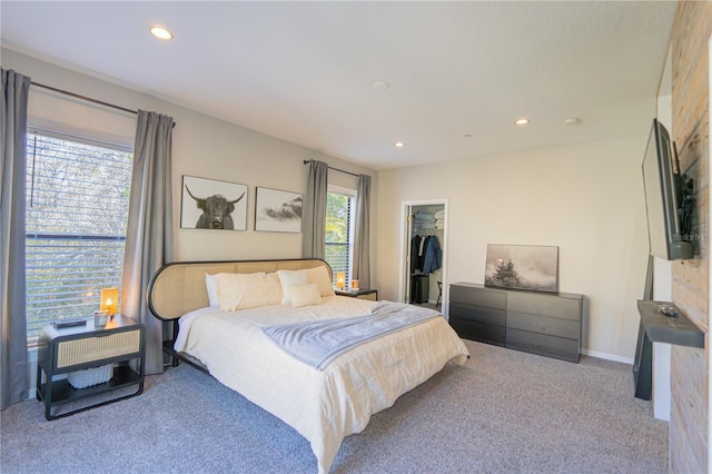 bedroom with multiple windows, a walk in closet, light colored carpet, and a closet