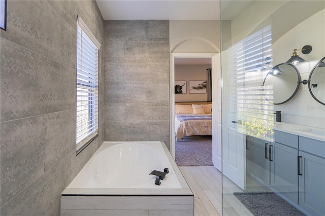 bathroom featuring vanity, tiled bath, and tile walls