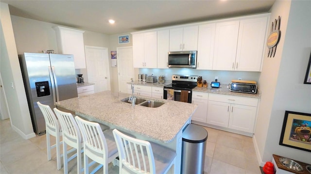 kitchen with sink, stainless steel appliances, an island with sink, and white cabinets