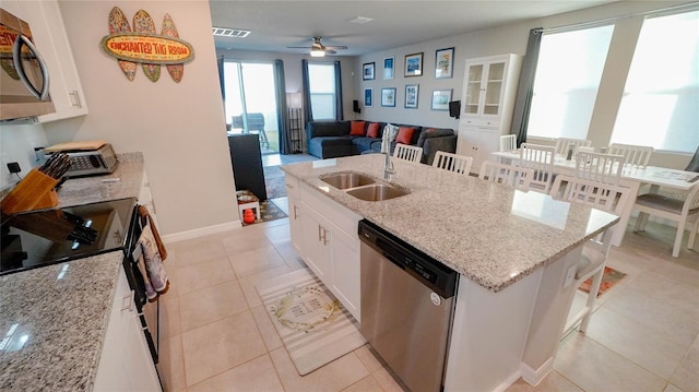 kitchen with light stone counters, stainless steel appliances, white cabinets, and a kitchen bar