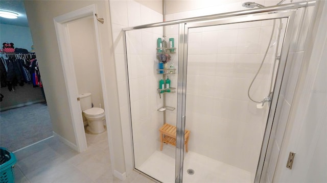 bathroom featuring tile patterned floors, a shower with door, and toilet