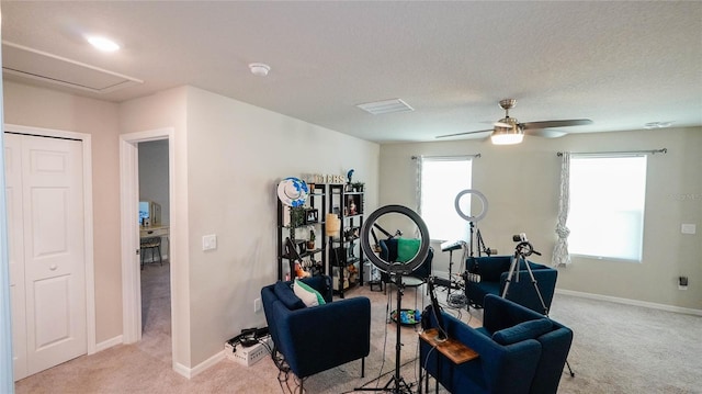 workout area featuring ceiling fan, light carpet, and a textured ceiling