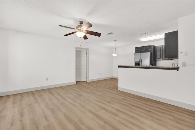 unfurnished living room with ceiling fan, a textured ceiling, and light hardwood / wood-style floors