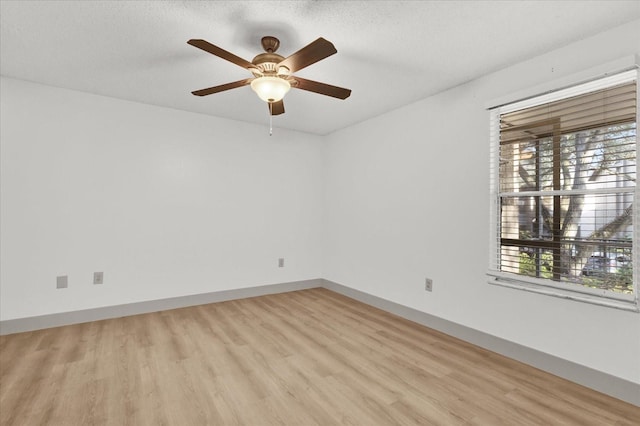 spare room with ceiling fan, a textured ceiling, and light wood-type flooring