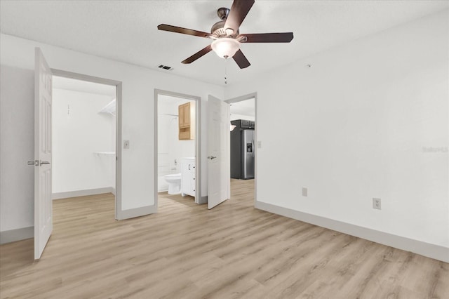 unfurnished bedroom featuring stainless steel fridge with ice dispenser, a spacious closet, light hardwood / wood-style flooring, and a closet