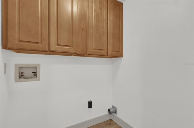 laundry area with hookup for a washing machine, light hardwood / wood-style floors, and cabinets