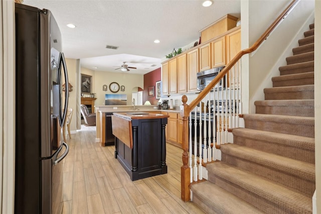 kitchen featuring light brown cabinetry, a kitchen island, ceiling fan, and appliances with stainless steel finishes