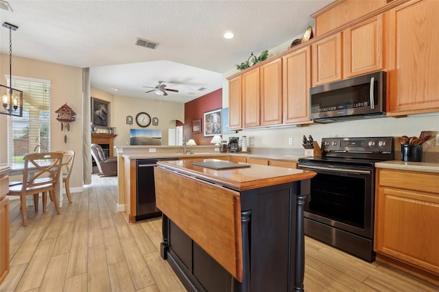 kitchen featuring appliances with stainless steel finishes, decorative light fixtures, kitchen peninsula, and light wood-type flooring