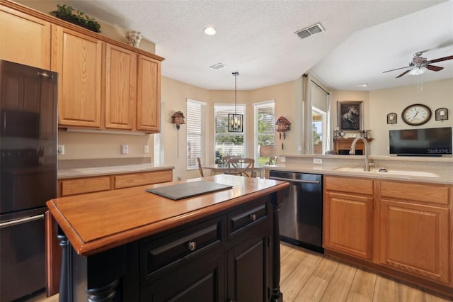 kitchen featuring hanging light fixtures, light hardwood / wood-style floors, a textured ceiling, black fridge, and stainless steel dishwasher