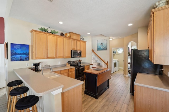 kitchen with kitchen peninsula, sink, light brown cabinets, and black appliances