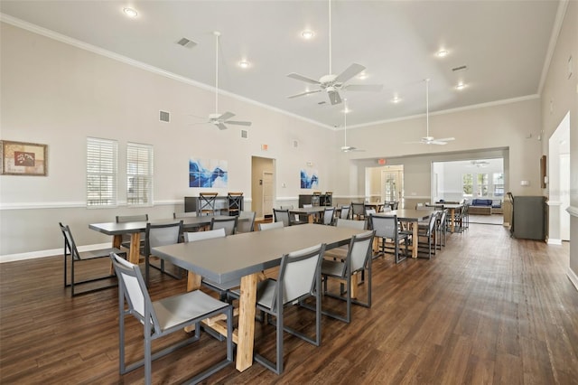 dining area featuring crown molding, dark wood-type flooring, and a high ceiling