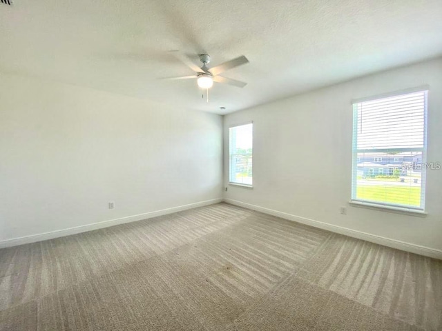 spare room featuring a textured ceiling, light colored carpet, and ceiling fan