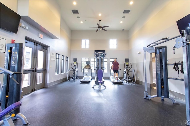 gym featuring a towering ceiling, ceiling fan, and french doors