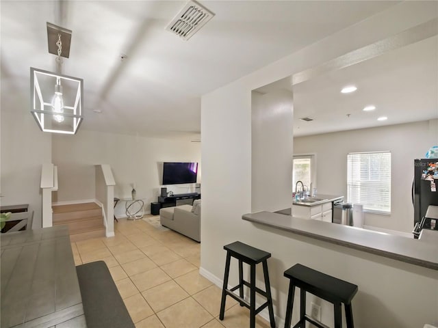 kitchen featuring sink, light tile patterned floors, black refrigerator, kitchen peninsula, and dishwasher