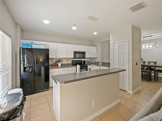 kitchen with white cabinets, light tile patterned floors, a center island with sink, and black appliances