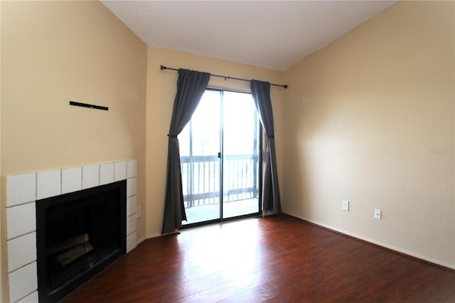 unfurnished living room featuring dark hardwood / wood-style floors and a tiled fireplace