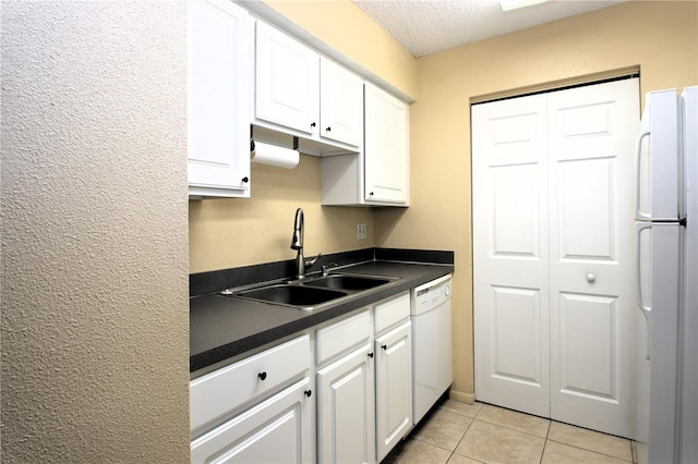 kitchen with sink, a textured ceiling, light tile patterned floors, white appliances, and white cabinets