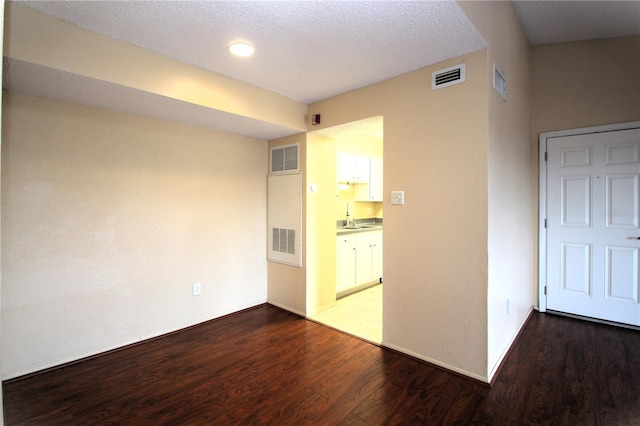 empty room featuring dark hardwood / wood-style floors, sink, and a textured ceiling