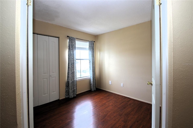 unfurnished bedroom featuring dark hardwood / wood-style flooring and a closet