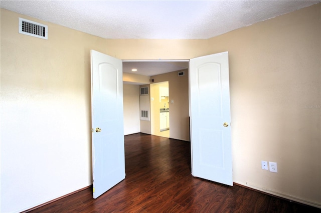 unfurnished room featuring dark wood-type flooring and a textured ceiling